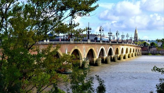 Vue panoramique du pont de Pierre, pont historique enjambant la Garonne à Bordeaux, en France, sous un ciel dégagé.