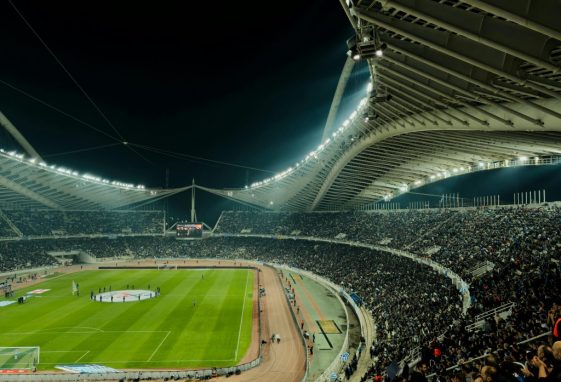 Un stade de football bondé sous des lumières vives la nuit, capturant l'excitation d'un événement sportif en direct.
