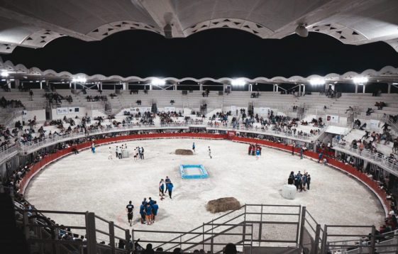 Une scène animée dans une arène sportive couverte remplie de spectateurs et de participants la nuit.